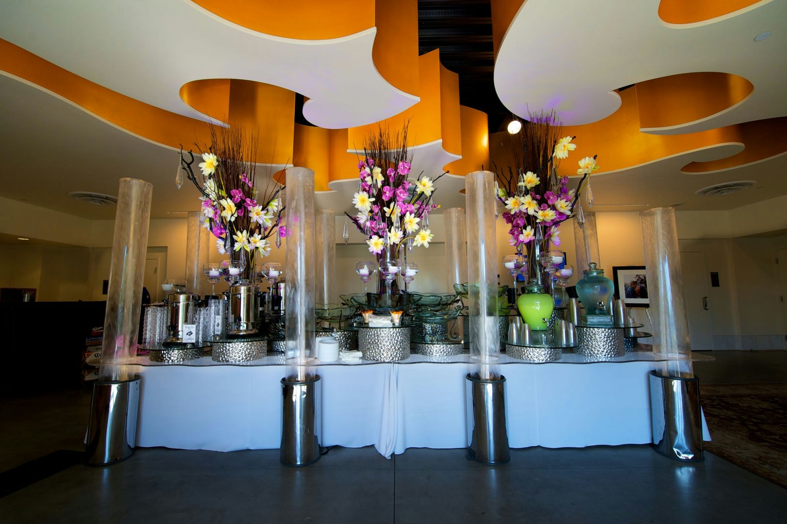 A banquet table with flowers, food, and drink. Stylish, modern interior.