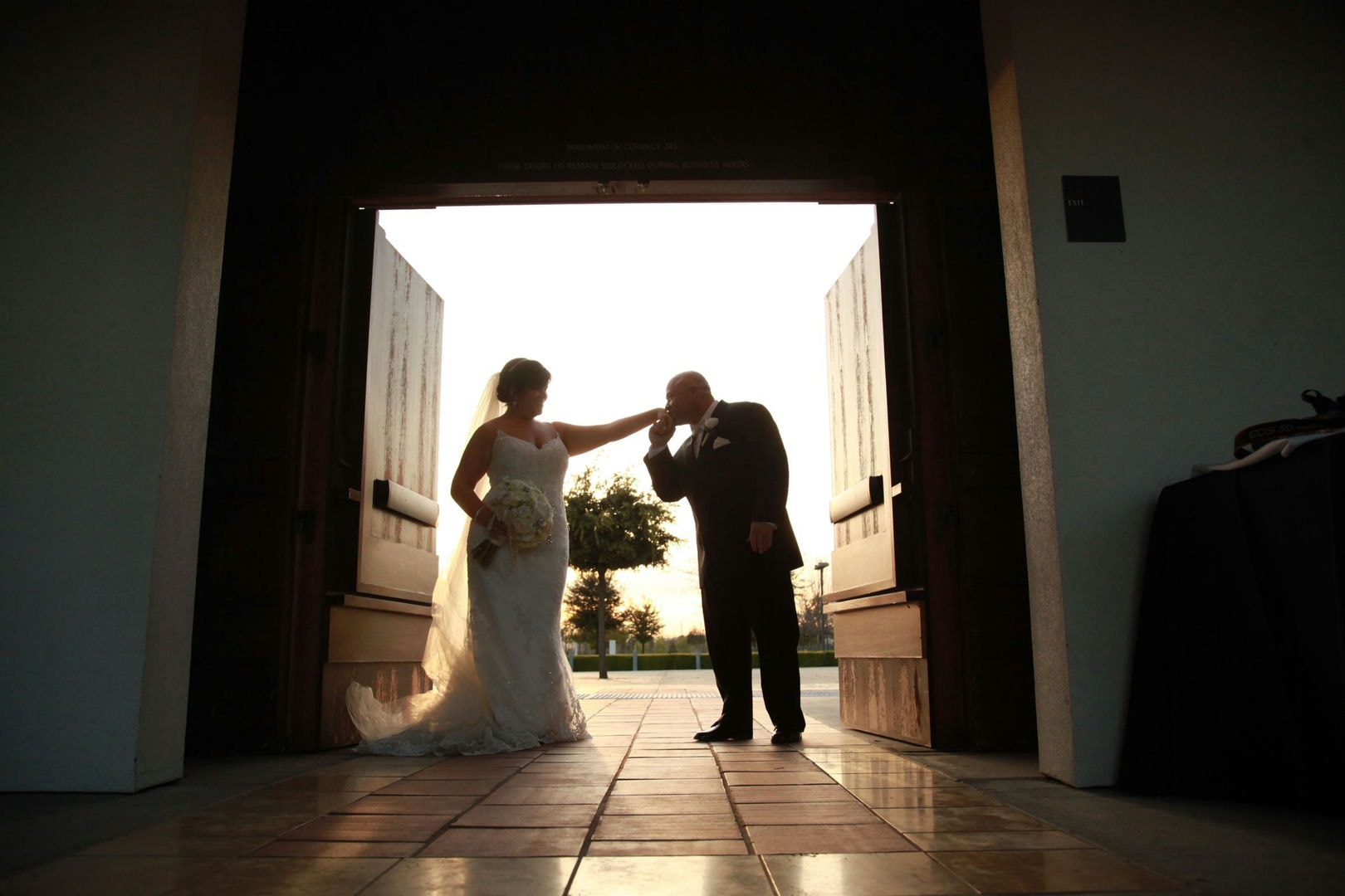 A bride and groom are standing in an open doorway. They appear to be at a wedding.