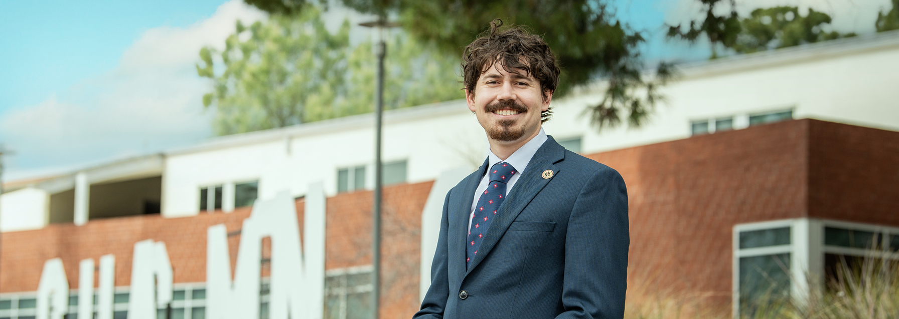 photo of student outside wearing a navy blue suit