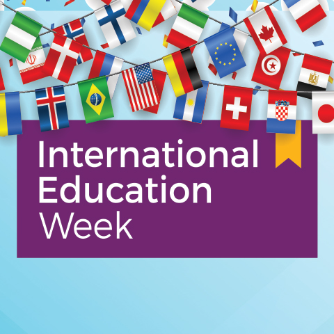 Many flags hang, with the words International Education Week on purple background.