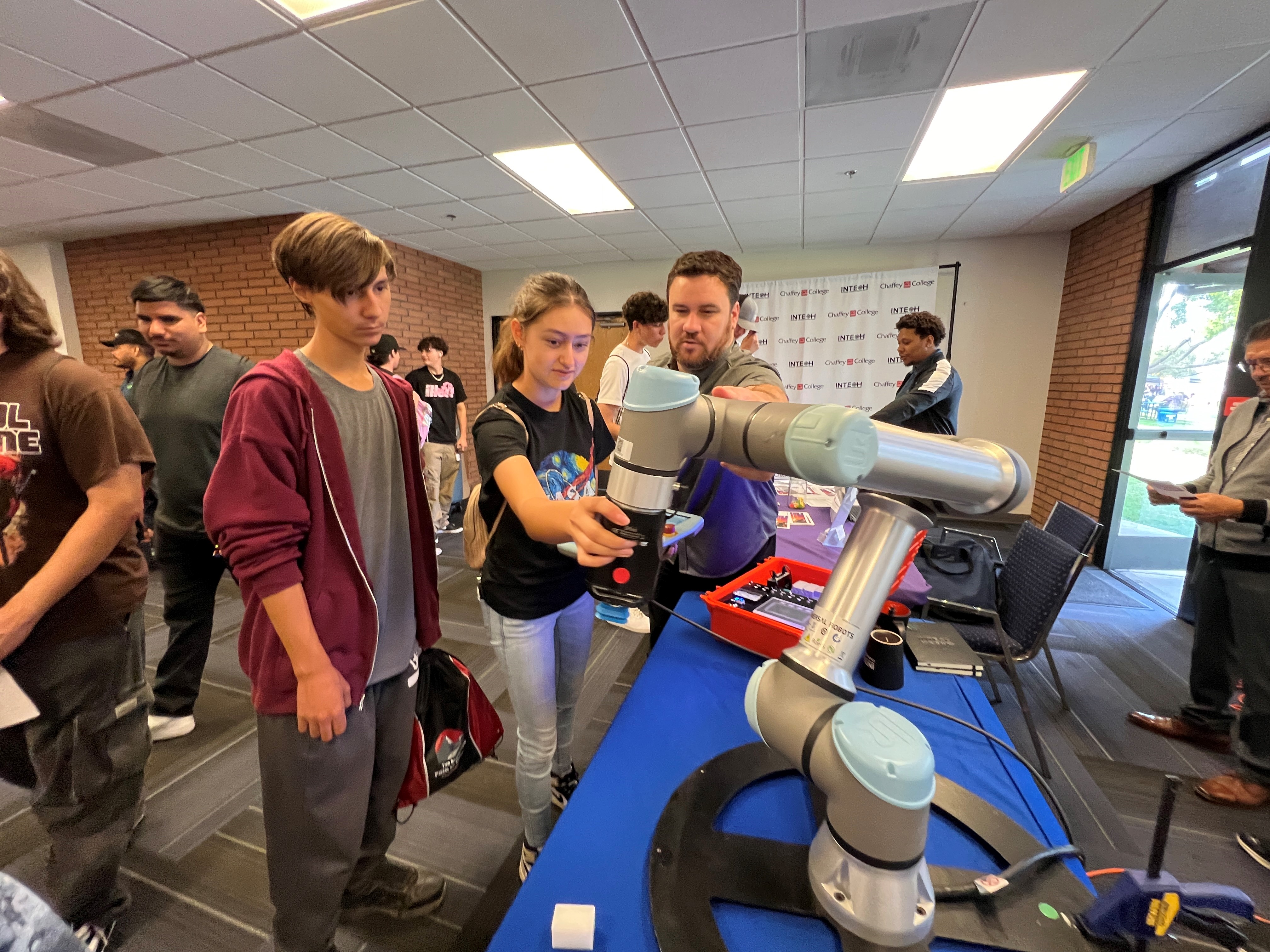 Students from Granite Hills High School examine a robotic arm at Manufacturing Day 2024.