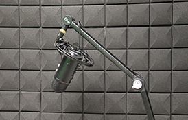 A microphone, headphones, and computer equipment are in a radio studio. &quot;On Air&quot; sign is visible.